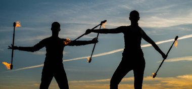 Ateşli göstericiler, gece gölgelerinde yanan bastonları dışarıda, gökyüzünde ve doğada manipüle ederler.