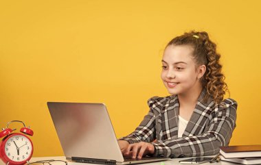 Laptop üzerinde çalış. Liseli kızın çevrimiçi ödevi var. Okula dönüyorum. Ders çalışma zamanı. Ofisteki küçük kız. Küçük iş kadını. Mutlu çocukluk. Kıvırcık saçlı çocuk ceket giyiyor.