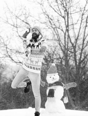 Mutlu ol. Mutlu hipster Noel 'e hazır. Kış mevsimi. Mutlu noeller. Kış tatili Soğuk havada sıcak kazak. Adam eğleniyor. Sakallı adam kardan adam yapar. Mutlu yıllar.