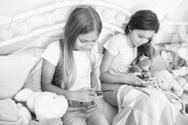 En iyi Noel mesajları. Küçük kızlar yatakta akıllı telefon kullanır. Noel ve Yeni Yıl 'ı telefonla selamlıyorum. Cep telefonu olan mutlu küçük çocuklar. Mutlu Noeller ve mutlu yıllar.