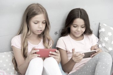 Çocuk eğlencesi başvurusu. İnternet sörfü ve ebeveynlik danışmanlığı yok. Akıllı telefon internet erişimi. Kız kardeşler akıllı telefonlarla meşgul pijama giyerler. Pijamalı çocuklar akıllı telefonlarla etkileşim halindedirler.