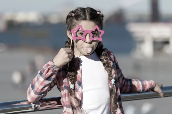 Getting ready for party. Small naughty girl having fun. Fashionable glasses for celebration. Stylish look. Disobedient small girl showing her tounge. Positive moments. Concept of childish carelessness — Stock Photo, Image