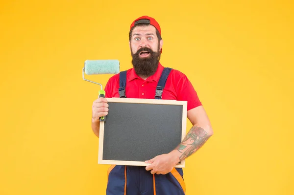 Здивований бородатий чоловік художник у костюмі котла з використанням інструменту для малювання стіни і тримання дошки для копіювання простору реклами, кваліфікований майстер хотів — стокове фото
