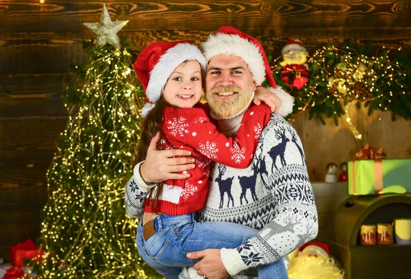 一緒にクリスマスパーティーだ。家族は家やクリスマスツリーを飾る。冬のクリスマス休暇。新年明けましておめでとう。髭を生やしたパパとサンタさんの帽子。面白いニットセーター。父と娘はクリスマスを祝う — ストック写真