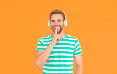 Müzikte sessizlik sesten daha önemlidir. Mutlu adam gizli jest yapar. Adam kulaklıkla müzik dinliyor. Ses ve müzik teknolojisi. Stereo sesi. Müzik çalarken sessizlik lütfen.