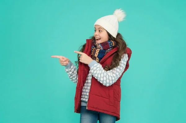 Publicidade roupa térmica. menina adolescente feliz usar roupas quentes. moda de criança de inverno. criança com cabelo encaracolado em tricotado chapéu poiting dedo. atividade de Natal estilo estação fria. felicidade infantil — Fotografia de Stock