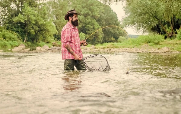 Summertime. hobby and sport activity. pothunter. mature man fly fishing. man catching fish. bearded fisher in water. fisherman with fishing rod. summer weekend. Big game fishing — Stock Photo, Image