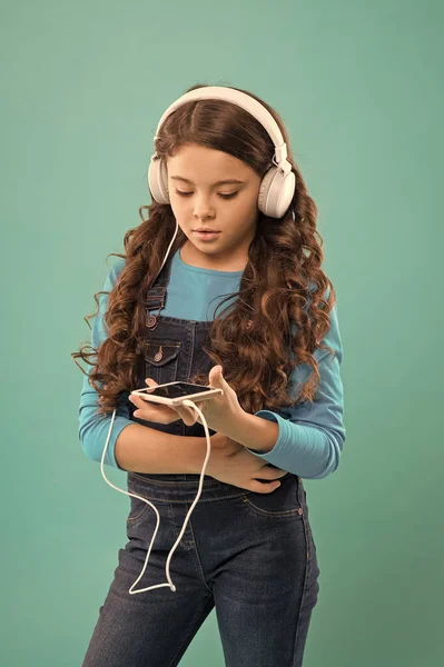 Dzieciak słucha muzyki w słuchawkach. małe dziecko zrobić listę odtwarzania na smartfonie. Mała dziewczynka trzymać odtwarzacz mp3. Wybieram ulubioną piosenkę. e-learning we współczesnym życiu. uczennica korzystać z nowych technologii — Zdjęcie stockowe