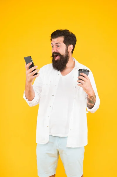 Spänning. Det moderna livet. Glad kille med mustasch och skägg dricker kaffe. läsa meddelande på smartphone. mogen skäggig man chattar på telefon och dricker kaffe. morgondryck i pappersmugg — Stockfoto