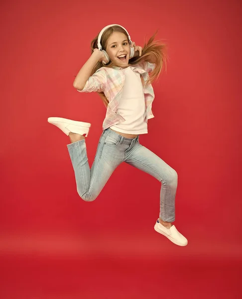 Niña con auriculares. alcanzar su sueño. saltar en el aire. logro. niña extática usar auriculares. Muestra movimiento de baile. felicidad infantil. niño feliz escuchar música. canción enérgica para la actividad — Foto de Stock