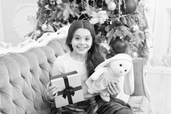 Felicitaciones sinceras. csmall girl love her bunny. mejor regalo de juguete de Navidad. niño heerful encontrar regalos en el árbol de Navidad. sentirse cómodo en casa. Feliz año nuevo. alegría y alegría. regalos de Navidad en la tienda de niños — Foto de Stock