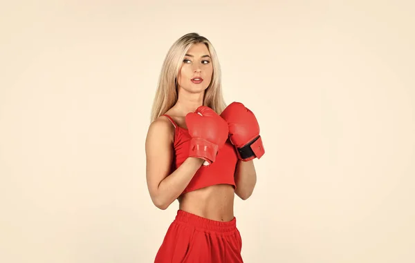 Full of energy. blond boxer woman. kick off. confident young sportswoman posing in boxing gloves. beautiful woman with red boxing gloves. young sports woman in tracksuit and boxing gloves