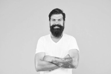 Sarı arka planda mutlu vahşi sakallı adam. Yakışıklı, kendine güvenen bir adamın mükemmel bir saç stili var. Erkek yüz bakımı. Vahşi sakallı adamın portresi. Düşünen şık adam gülümsüyor.