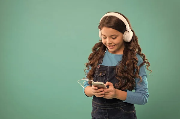 Rozrywka online. Darmowe aplikacje muzyczne. Słuchaj za darmo. Zdobądź subskrypcję konta muzycznego. Ciesz się muzyką. Ciesz się doskonałym dźwiękiem. Mała dziewczynka dziecko słuchać muzyki nowoczesne słuchawki i smartfon — Zdjęcie stockowe