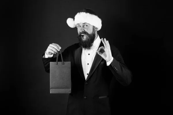 Прекрасный подарок. Счастливый бизнесмен показывает знак ОК. Бородатый мужчина улыбается с подарком в сумке. Покупаю рождественский подарок. День бокса. Новогодний сюрприз. Вечеринка. Подарок от босса к эмпойе, место для копирования — стоковое фото