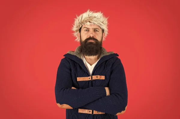 Kleding ontwerp. Man met baard staan warme trui en hoed op rode achtergrond. Winterseizoen herenkleding. Hipster rustieke stijl harige hoed. Een modewinkel. Een mannelijk kledingconcept. Winterkleding — Stockfoto