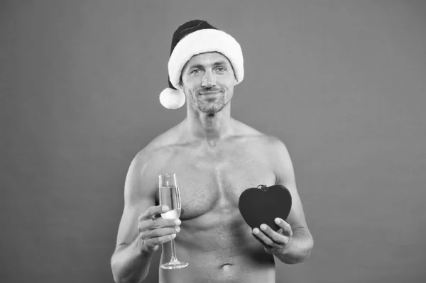 Σέξι Άι Βασίλης. μυώδης άνθρωπος Σάντα καπέλο κόκκινο φόντο. αφρώδες κρασί και δώρο. Πρωτοχρονιάτικες ευχές. Χριστουγεννιάτικο πάρτι για ενήλικες. Όμορφος Άγιος Βασίλης ερωτευμένος. ρομαντική Χριστουγεννιάτικη βραδιά. καλύτερο χριστουγεννιάτικο δώρο — Φωτογραφία Αρχείου