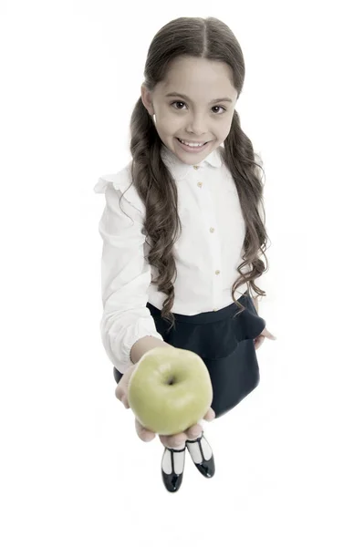 Niña linda pupila tiene fruta de manzana fondo blanco. Niño niña ropa de uniforme escolar ofrece manzana. Niño inteligente niño sonriendo cara elegir bocadillo saludable. Concepto de almuerzo escolar. Nutrición saludable —  Fotos de Stock