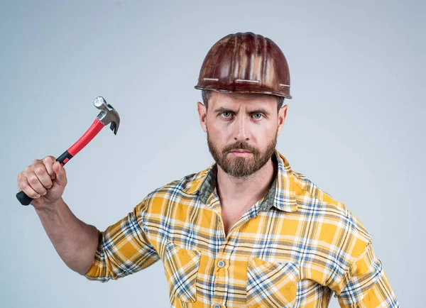 Schöner Mann Schreiner mit Bauschutzhelm und kariertem Hemd auf Baustelle mit Hammer, Wartung — Stockfoto