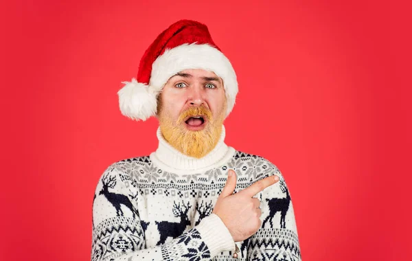 Festa del Natale. Natale e 'l'ora dello shopping. maturo maschio maglia maglione di Natale. L'uomo brutale odia le vacanze invernali. Babbo Natale uomo sorpreso cappello. capelli barbuti hipster tinti sfondo rosso. festa di Capodanno — Foto Stock