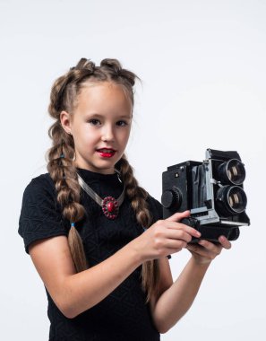 Retro kameralı şık bir kız beyaz fotoğrafçılıkta izole edilmiş bir fotoğraf çekiyor.