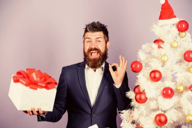 Gizli Noel Baba konsepti. Kış tatili Noel selamları. Meslektaşlarım için en iyi hediyeler. Ofis noel partisi. Adam sakallı hippi resmi takımı Noel ağacının yanında. Noel hediyeleri ve dekorasyonlar