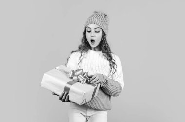 Çocuk hediyesini açarken heyecanlanıyor. Kızım için Noel hediyesi. Sürprizlerin. Küçük kız, sarı arka planda kurdelesi olan hediye kutusunu tutuyor. Genç kız tatil hediyesi aldı. En iyi Noel hediyeleri.