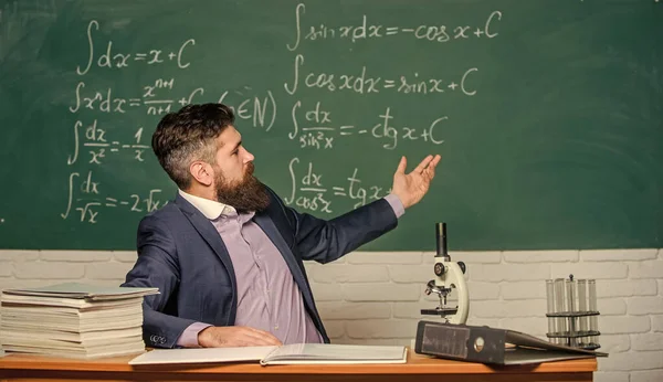 Lärare karismatisk hipster sitta vid bord klassrum chalkboard bakgrund. Ett pedagogiskt samtal. Pratar med studenter eller elever. Lärarkoncept. Lärare skäggig man berätta intressant historia — Stockfoto