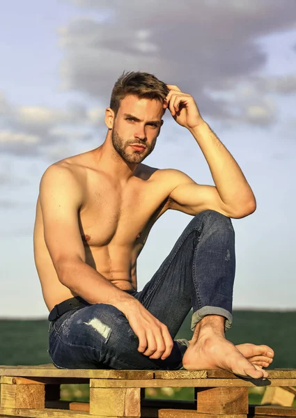 Modèle de fitness. Un beau macho sportif porte un pantalon en denim. Corps musculaire. Torse nu musclé. Six paquets de poitrine musculaire. Homme en plein air fond bleu ciel. Concept de beauté masculine. lookbook d'été — Photo