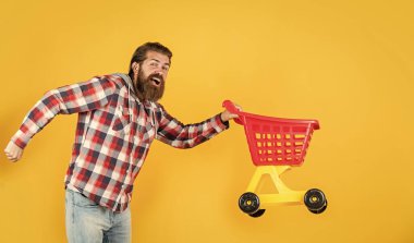 Dükkanda. Başarılı alışverişler yapıyor. Vahşi yetişkin hipster alışverişe gidiyor. Arabayı doldurma zamanı. Adam alışverişe gider. Küçük alışveriş arabalı komik adam. Ürün satın alma üzerine hafta sonu