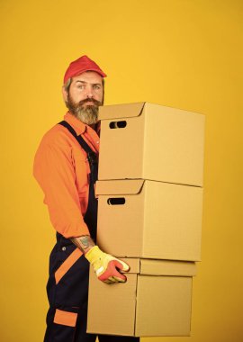 Kutu paketleyen bir adam. Yeni bir daireye taşınmak. Üniformalı sakallı yükleyici. Karton kutular yeni bir eve taşınıyor. yeni bir konaklama ya da oda onarımı