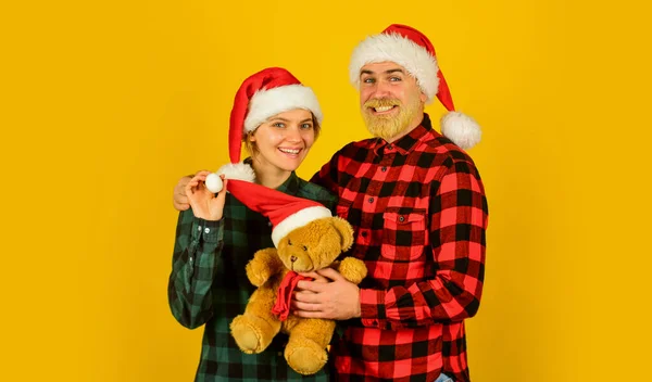 Noel 'i seviyoruz. Oyuncak ayıya aşık çift Noel tatilinin tadını çıkarır. Aile Noel Baba şapkası. Yetişkinler için eğlence fikirleri. Aile tatili. Sevgi dolu çift sarı arka plan. Noel zamanı — Stok fotoğraf
