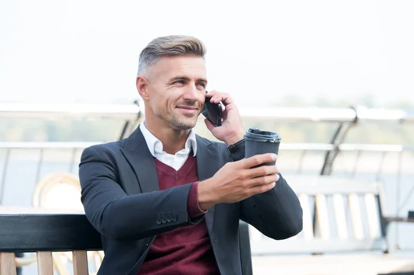 Happy manager tratar taza de café para llevar hablando en el teléfono móvil al aire libre, disfrutar — Foto de Stock