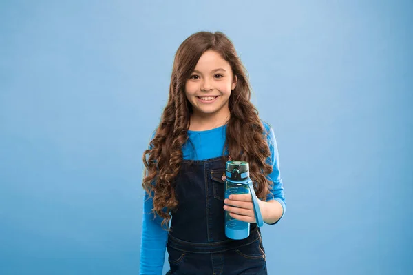 Drink some liquids. Water balance concept. Strong and healthy child. Living healthy life. Health and water balance. Girl hold water bottle blue background. Kid girl long hair has water bottle Stock Image