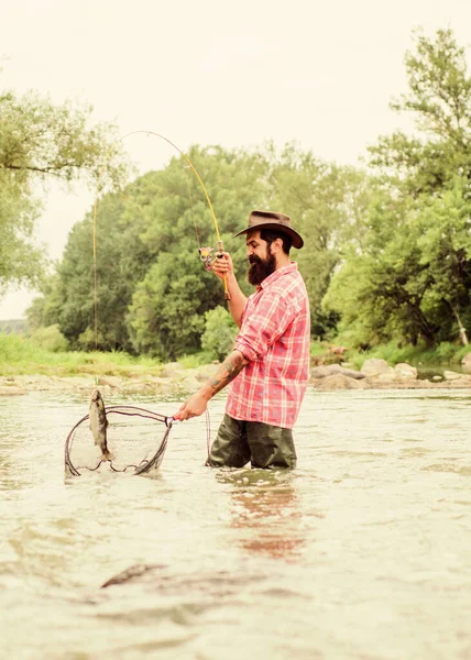 Als je regelmatig vist weet je hoe lonend en rustgevend vissen is. Vissen is een verbazingwekkend toegankelijke recreatieve buitensport. Baard brutale visser vangen forel vis met net. Visserijhobby — Stockfoto