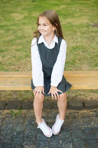 Glad liten flicka barn i formell skoluniform sitta på parkbänk, skolflicka — Stockfoto