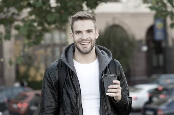 Šťastné ráno. Hipster drží papírový šálek kávy. Pauza na kafe. Vypij to na cestu. Muž usmívající se veselý hipster držet kávu vzít pryč. Student pije kávu venku. Rituály určují charakter — Stock fotografie