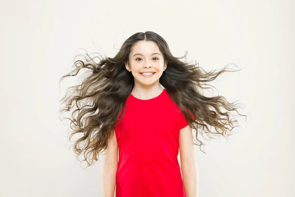 Me solté el pelo. Niño feliz con el pelo que fluye sobre fondo amarillo. Niño pequeño con linda sonrisa y cabello ondulado texturizado. Adorable niña pequeña sonriendo con el pelo largo morena — Foto de Stock