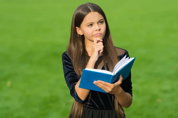 Think clearly and rationally. Serious child think holding book green grass. Critical and creative thinking skills. Making decision. Doing homework assignment. Intellectual growth. Education school
