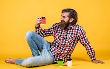 Güzel tat. Günaydın. Enerjik, sıcak içecek. İlham almak için kahve lazım. Mutlu sakallı adam sabah kahvesini içiyor. Adam kağıt bardaktan sıcak çay içiyor.