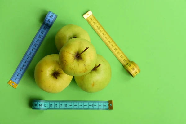 Äpplen nära mäta tejp rullar på grön bakgrund, ovanifrån — Stockfoto
