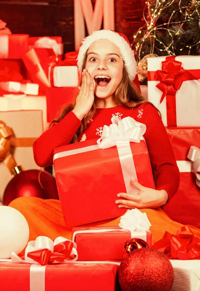 Niño en sombrero de santa con muchas cajas de regalo. compras exitosas en el mercado de Navidad. decorado con regalos. paquetes de compras venta de Navidad. alegre santa ayudante tipo regalos. asistente de tienda sonriente —  Fotos de Stock