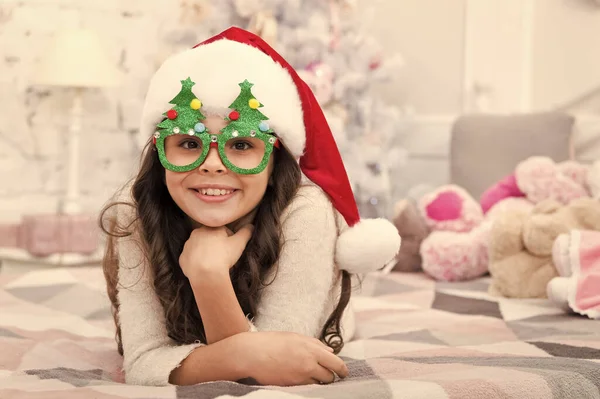 Small child wear santa hat celebrate new year at home decorated interior background. Girl kid in bedroom with toys. Happy new year. Wish list. Holidays atmosphere. Christmas spirit. New year holiday — Stock Photo, Image