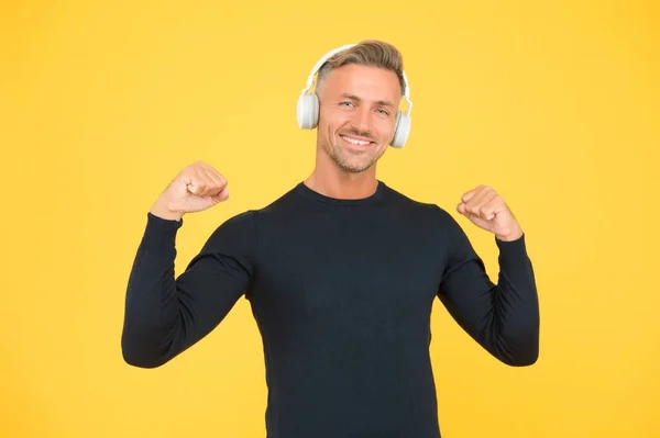 Bel homme heureux écouter de la musique dans des écouteurs élégants sur fond jaune, la technologie moderne — Photo