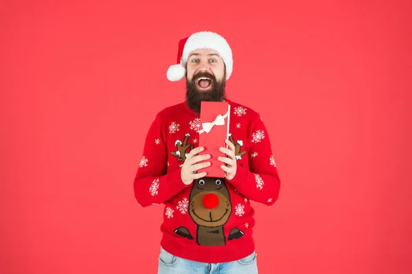 Karácsonyi bevásárlás. Készíts ajándékokat és ajándékokat. Boldog szakállas ember télapó kalapban. Szilveszteri buli. ünnepeljük a téli ünnepeket. Boldog karácsonyt! Egy férfi vicces kötött pulóverben dobozzal. Mi van benne? — Stock Fotó