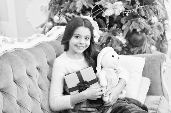 휴일 분위기. 최고의 크리스마스 장난감 선물이야. 크리스마스 트리에서 선물을 찾는 쾌활 한아이. 집에서 아늑 함을 느끼는 것. 새해 복 많이 받아. 응원 과 즐거움. xmas presents at kid shop. 토끼를 사랑하는 작은 소녀 — 스톡 사진
