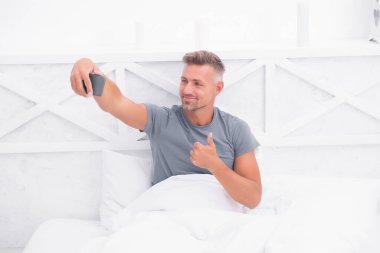 İyi sabahlar. İnternet günlüğü içeriği. Kişisel blog konsepti. İyi sabahlar. Fotoğraflı akıllı telefon kullanan bir adam. Çevrimiçi video yayınlanıyor. Gezici internet. Blog için çekim. Olgun bir blogcu. Başparmak yukarı.