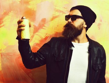 Sakallı vahşi beyaz hippi elinde sprey boya tutuyordu.