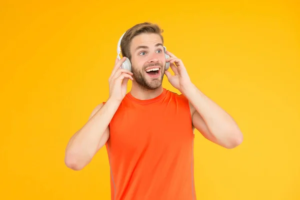 Χαρούμενος νεαρός άνδρας στα αθλητικά ρούχα φορούν σύγχρονα ακουστικά ακούγοντας μουσική κατά την εκπαίδευση, μουσική αθλητισμού — Φωτογραφία Αρχείου