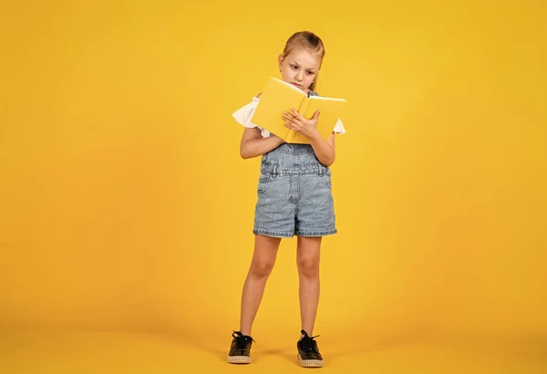 Que história interessante. Pronto para leitura. lição de literatura. de volta à escola. desenvolvimento de crianças inteligentes. expressar interesse e inteligência. menina pequena segurar notebook. ler o livro — Fotografia de Stock